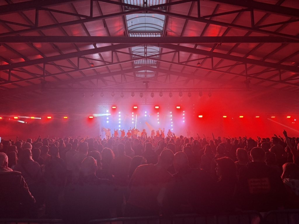 Concert en hall, public et scène sous éclairage rouge