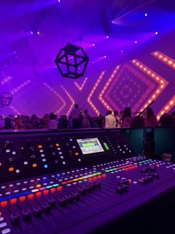 Console de mixage en régie façade pendant une soirée, lumière violette et décor LED